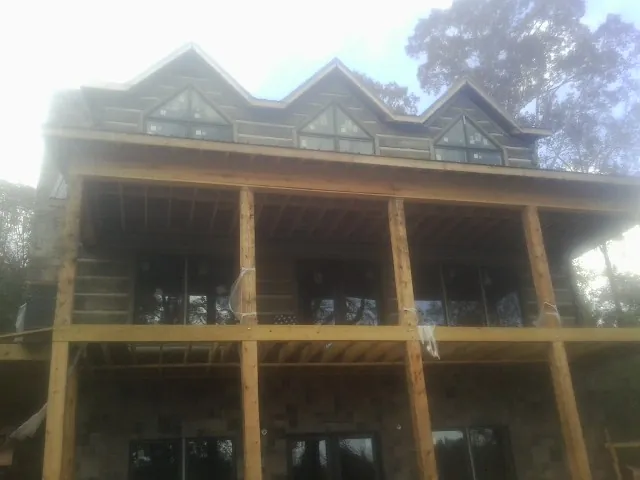 Dormers and porch framing on a large log home under construction — Roof Coating work by our crew in Lake Wales