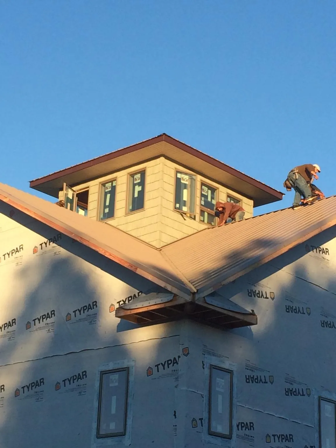 Roofers working around a rooftop cupola on a new metal roof at sunset — Roof Waterproofing in Lake Wales by Roofing Brothers
